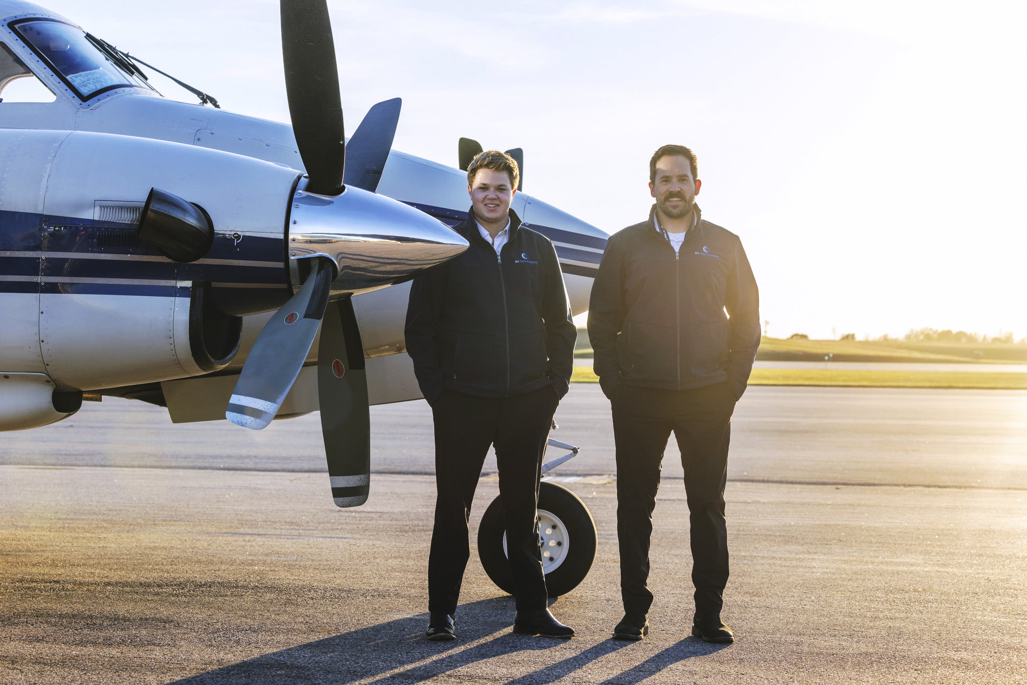 Pilots standing by a private jet and smiing