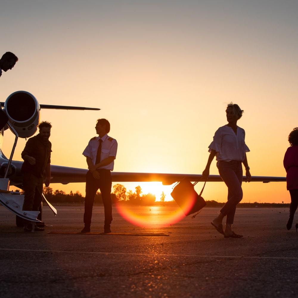 people exiting a plane during sunset