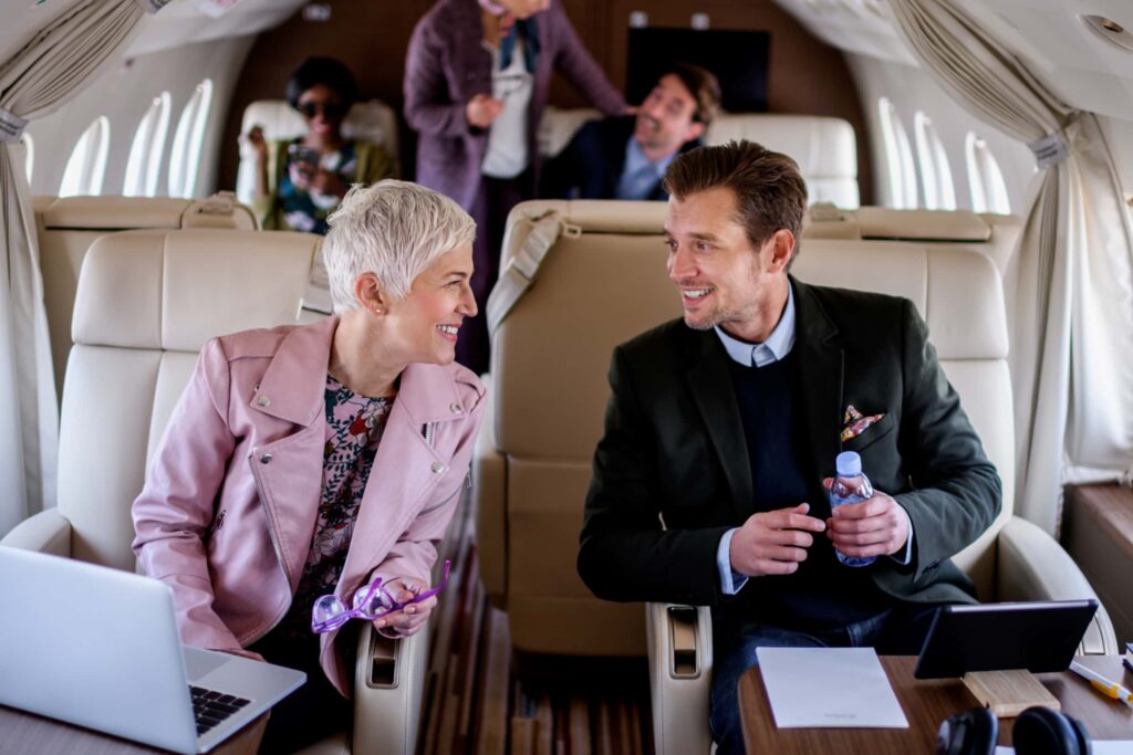 business partners smiling while talking on a private jet